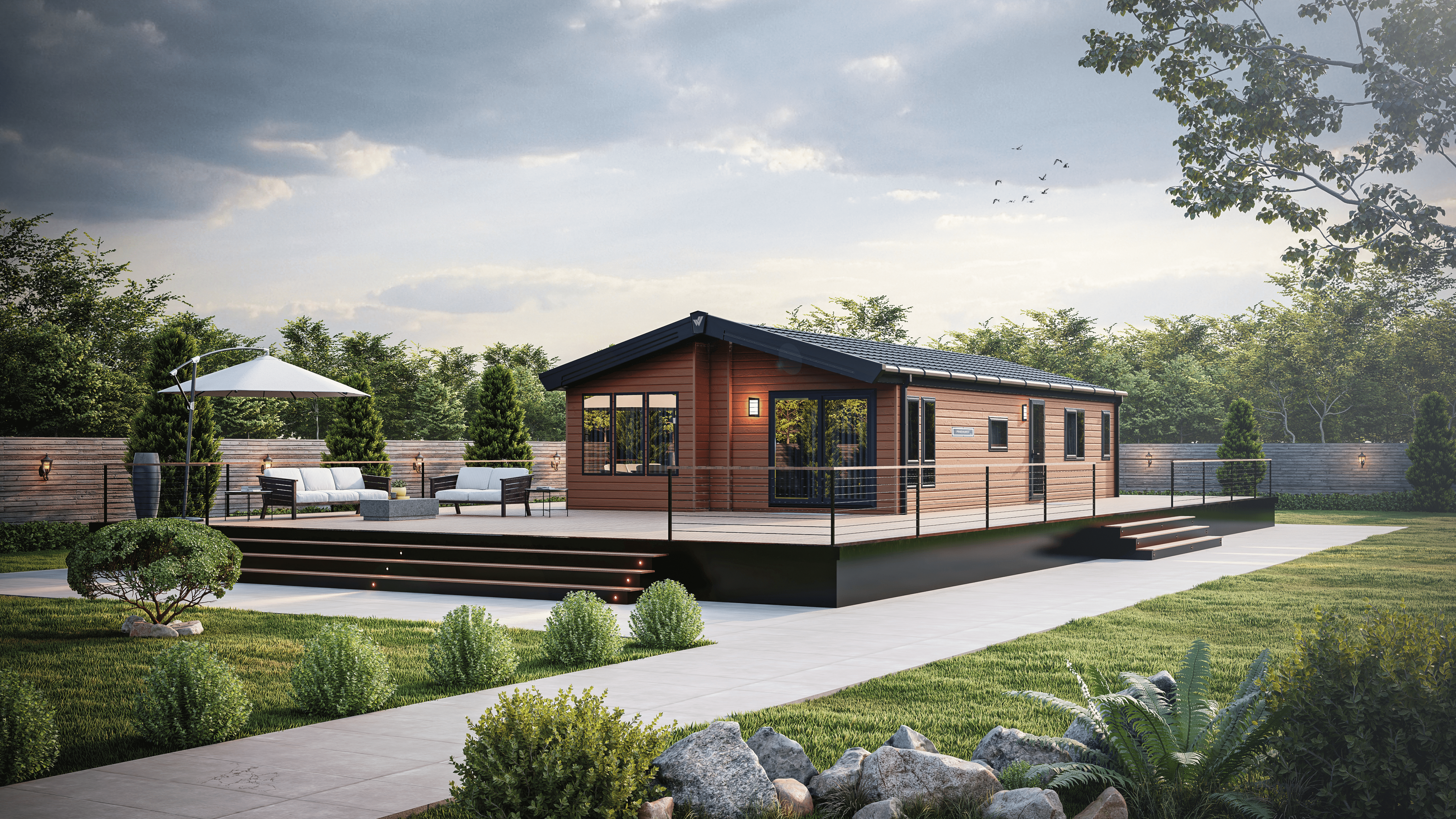 Scenic shot of the Willerby Pinehurst luxury lodge in a landscaped garden with paved path way and decking