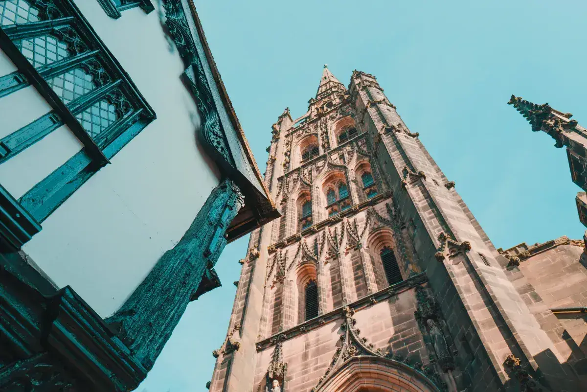 A low-angle shot of Coventry Cathedral tower against a blue sky. 
