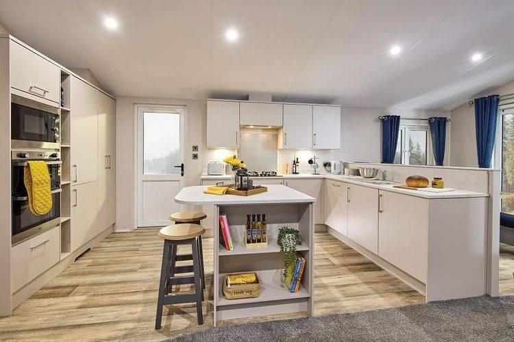 The Willerby Hayward C- shaped kitchen with white cupboards and worktops which has a kitchen island in the centre.