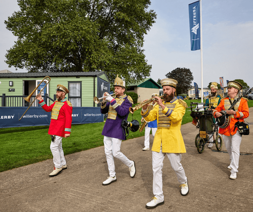A band plays there instruments in the sun at the Great Holiday Home Show in front of a Willerby caravan