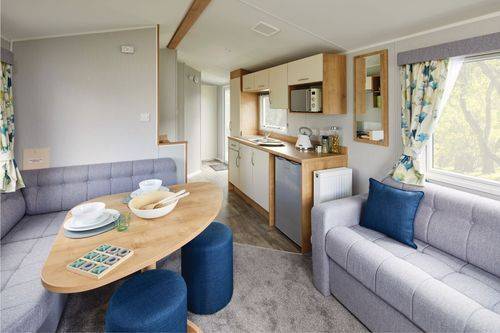 The Willerby Ashurst dining area with a grey corner seating and two blue stools surrounding a curved corner table. 