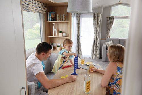 The Willerby Castleton dining area with a family of three playing a game of connect four, sat on a grey fixed window seat.