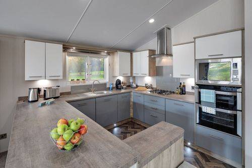 The Willerby Clearwater G-shaped kitchen is adorned with grey and white cupboard doors.