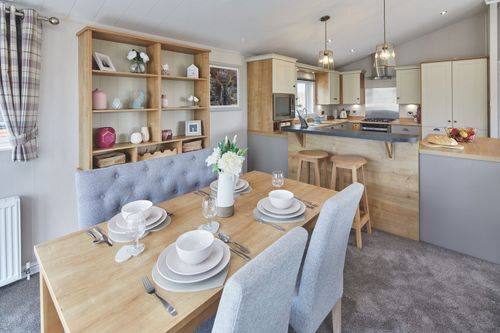 The Willerby Portland dining area has grey chairs surrounding an oak effect table, with an oak effect ornament unit behind.