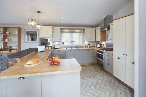 The Willerby Portland G-shaped kitchen has grey and white cupboard doors with an oak effect worktop.