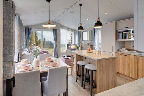 The Willerby Waverley kitchen has oak effect kitchen units with grey worktops and a matching kitchen island.