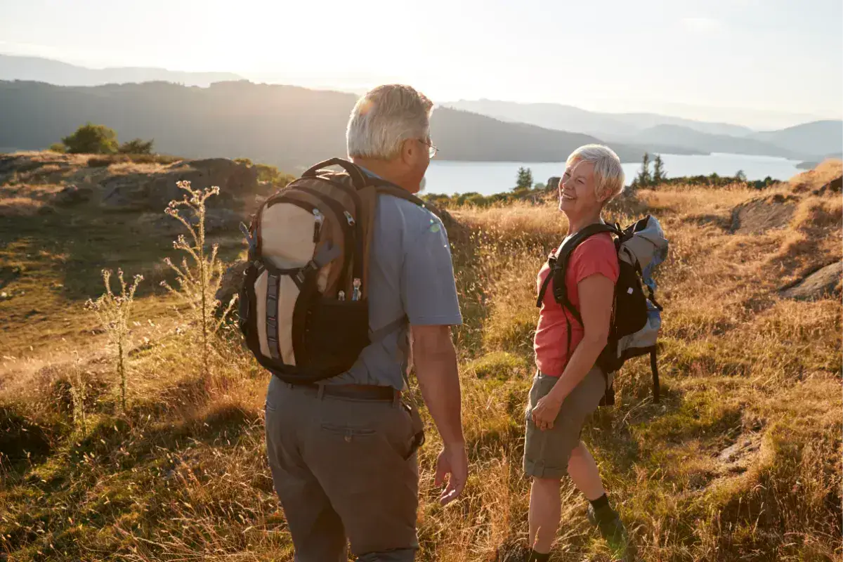 A couple hiking in the hills above a lake in the Lake District.