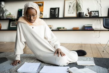 Woman reading notes in notebook in living room; Photo by Monstera from Pexels