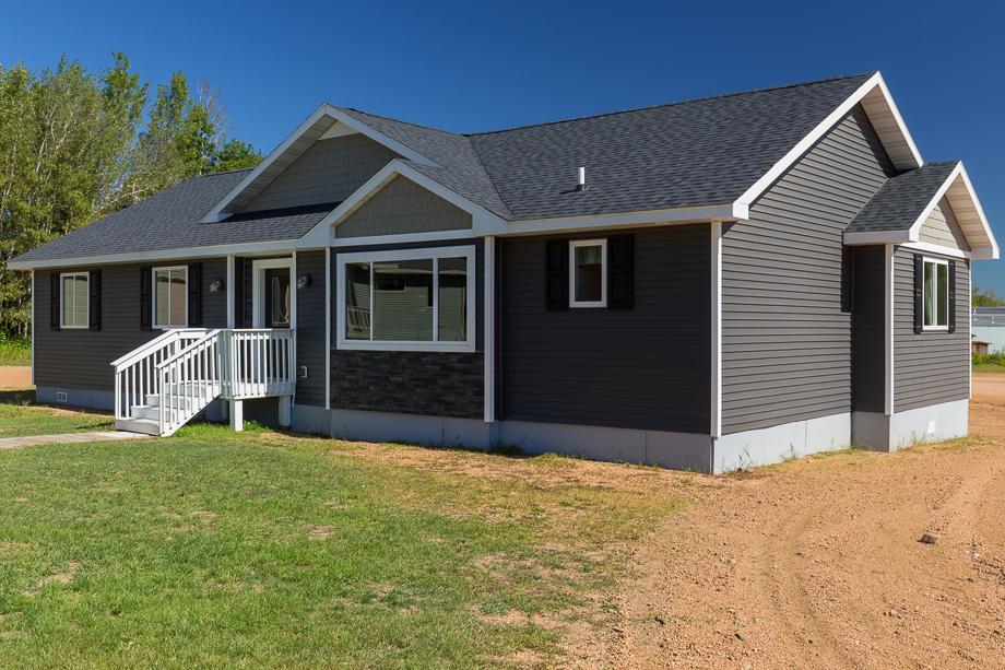 Dark gray ranch-style modular home with white trim, front steps, and gable roof by Wisconsin Homes.