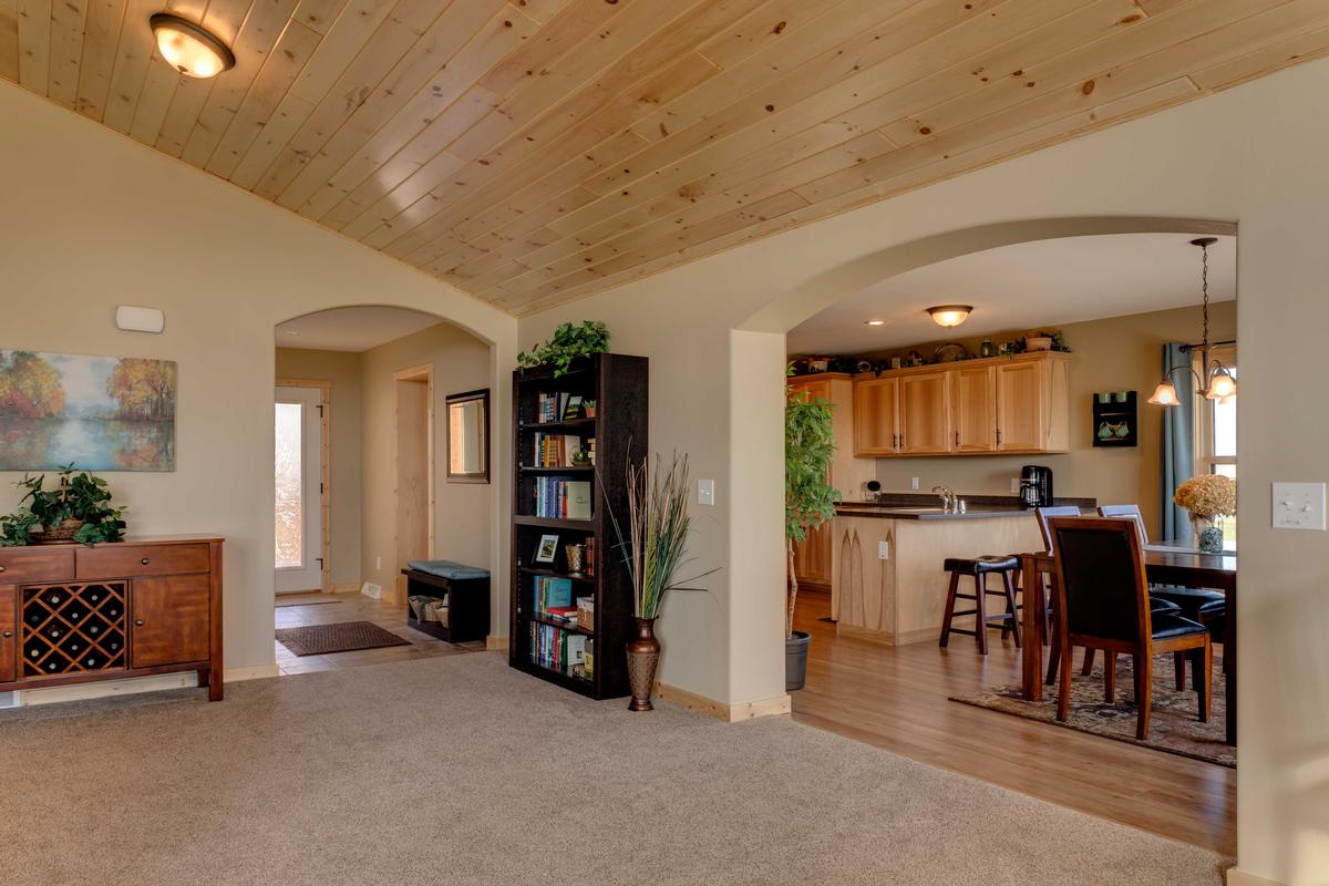 Open-concept kitchen and dining area with wood cabinetry in a cottage-style home by Wisconsin Homes.