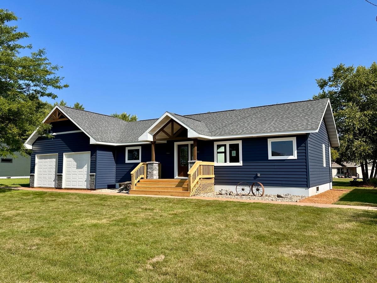 Ranch-style modular home with navy blue siding, gable porch entry, and attached garage by Wisconsin Homes.