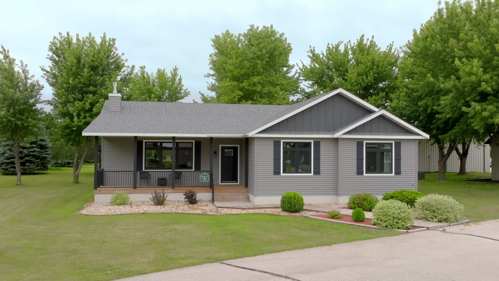 Gray ranch-style model home with front porch and black shutters by Wisconsin Homes.