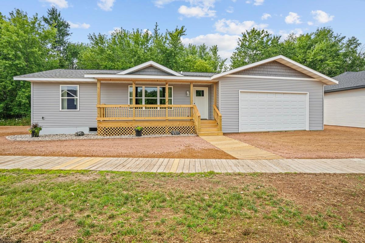 Ranch-style modular home with gray siding, front porch, and attached garage by Wisconsin Homes.