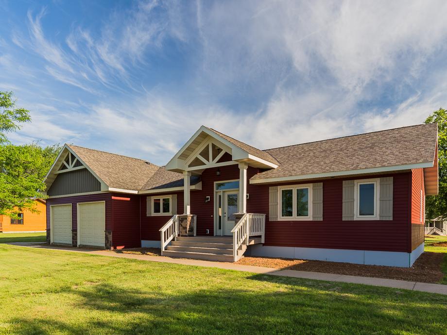 Red ranch-style modular home with gabled front entry, tan shutters, and attached garage by Wisconsin Homes.