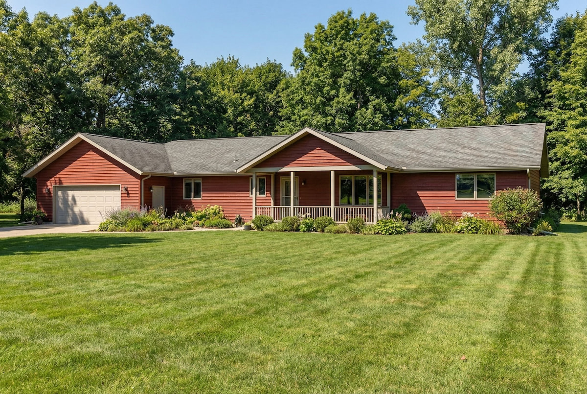 Red ranch-style modular home by Wisconsin Homes with beige trim, front porch, and attached garage in Marshfield, WI.