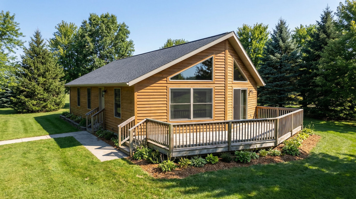 Compact cottage-style modular home by Wisconsin Homes in Marshfield, WI with wood siding and wraparound deck.