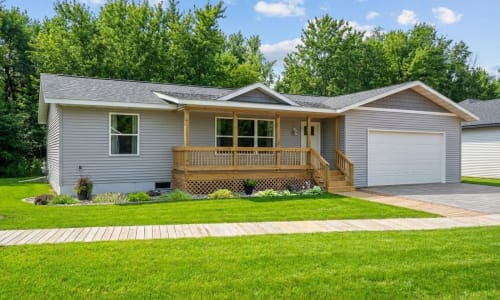 Ranch-style modular home with gray siding, front porch, and attached garage by Wisconsin Homes.