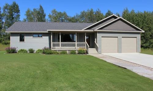 Light gray ranch-style modular home with covered front porch and two-car garage by Wisconsin Homes.