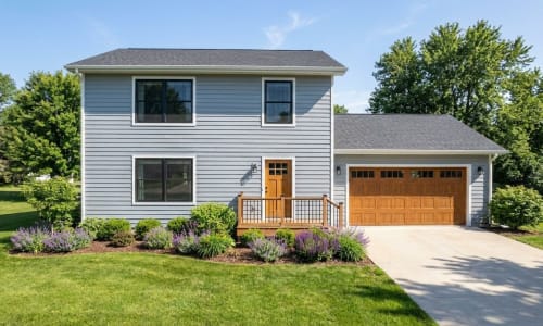 Blue Colonial-style modular home by Wisconsin Homes in Marshfield, WI with wood-tone door and garage.