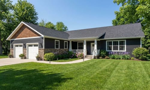 Dark blue modular home with stone-accented garage, covered porch, and landscaped yard by Wisconsin Homes in Marshfield, WI.