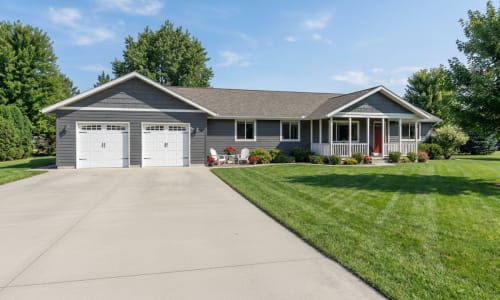 Gray ranch-style modular home by Wisconsin Homes with white garage doors and a covered front porch in Marshfield, WI.