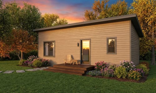 Minimalist cottage-style modular home by Wisconsin Homes in Marshfield, WI at sunset, featuring flat roof, compact design, and flower-lined deck.