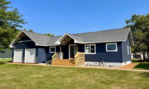 Ranch-style modular home with navy blue siding, gable porch entry, and attached garage by Wisconsin Homes.