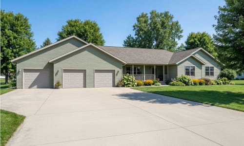 Sage green ranch-style modular home by Wisconsin Homes with triple garage and covered front porch in Marshfield, WI.