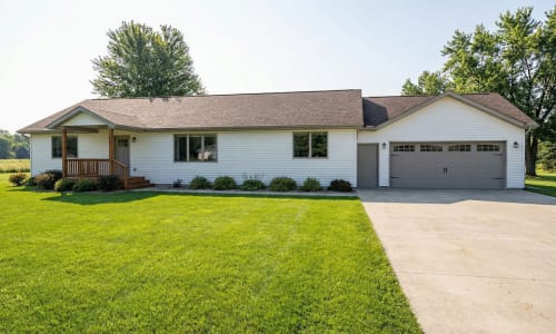 White modular ranch home by Wisconsin Homes with gray garage doors and wood-accented front porch in Marshfield, WI.