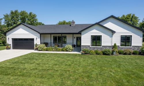 White ranch-style modular home by Wisconsin Homes with black trim, stone base, and black garage door in Marshfield, WI.