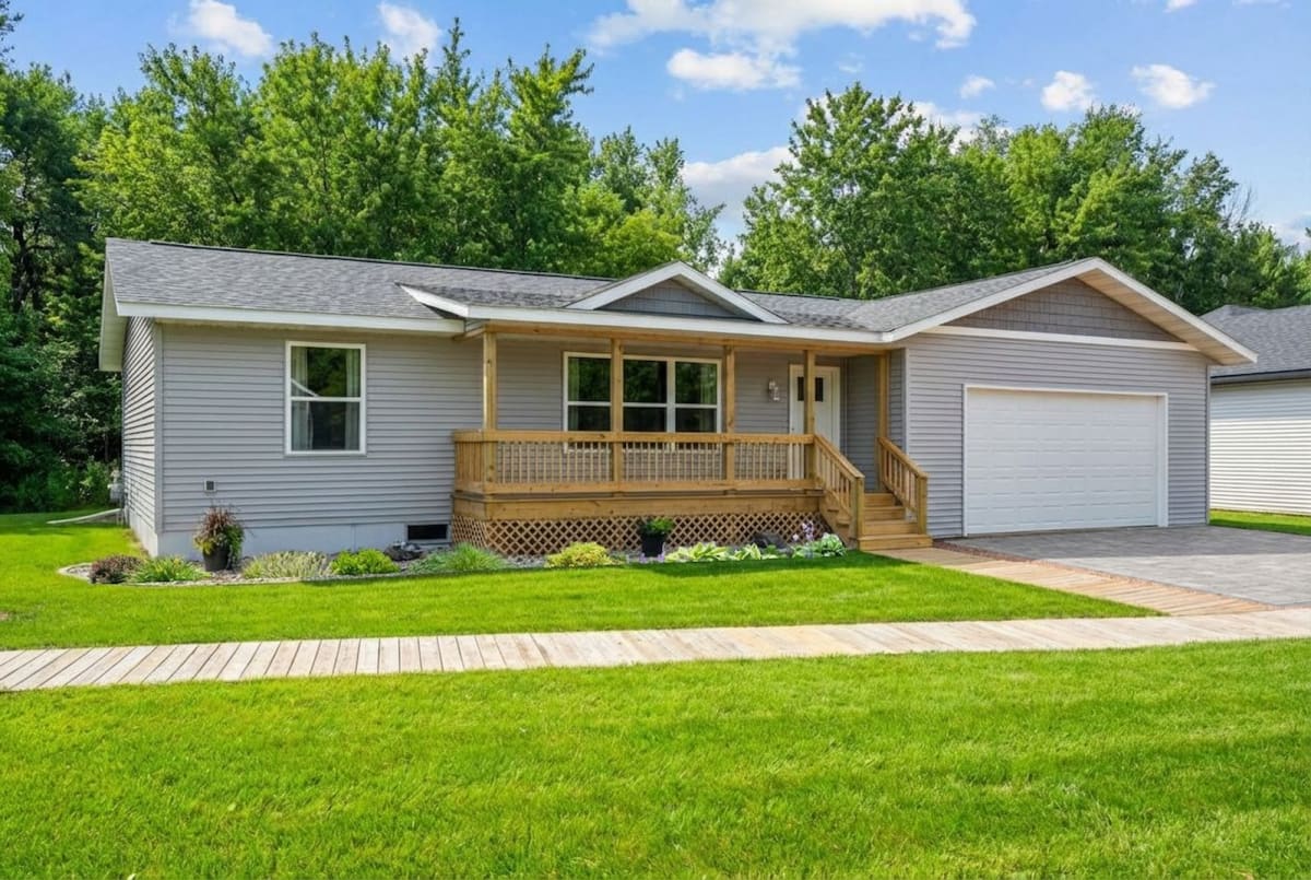 Ranch-style modular home with gray siding, front porch, and attached garage by Wisconsin Homes.