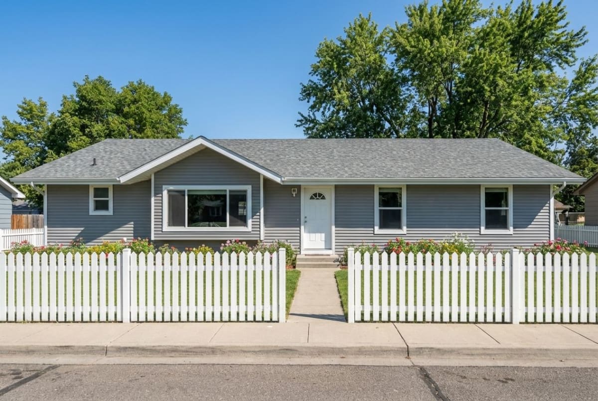 Gray modular ranch home with white picket fence and flower beds by Wisconsin Homes in Marshfield, WI.