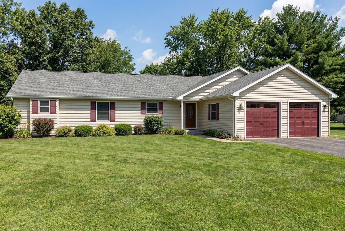 Single-story modular ranch home by Wisconsin Homes with tan siding and red garage doors in Marshfield, WI.