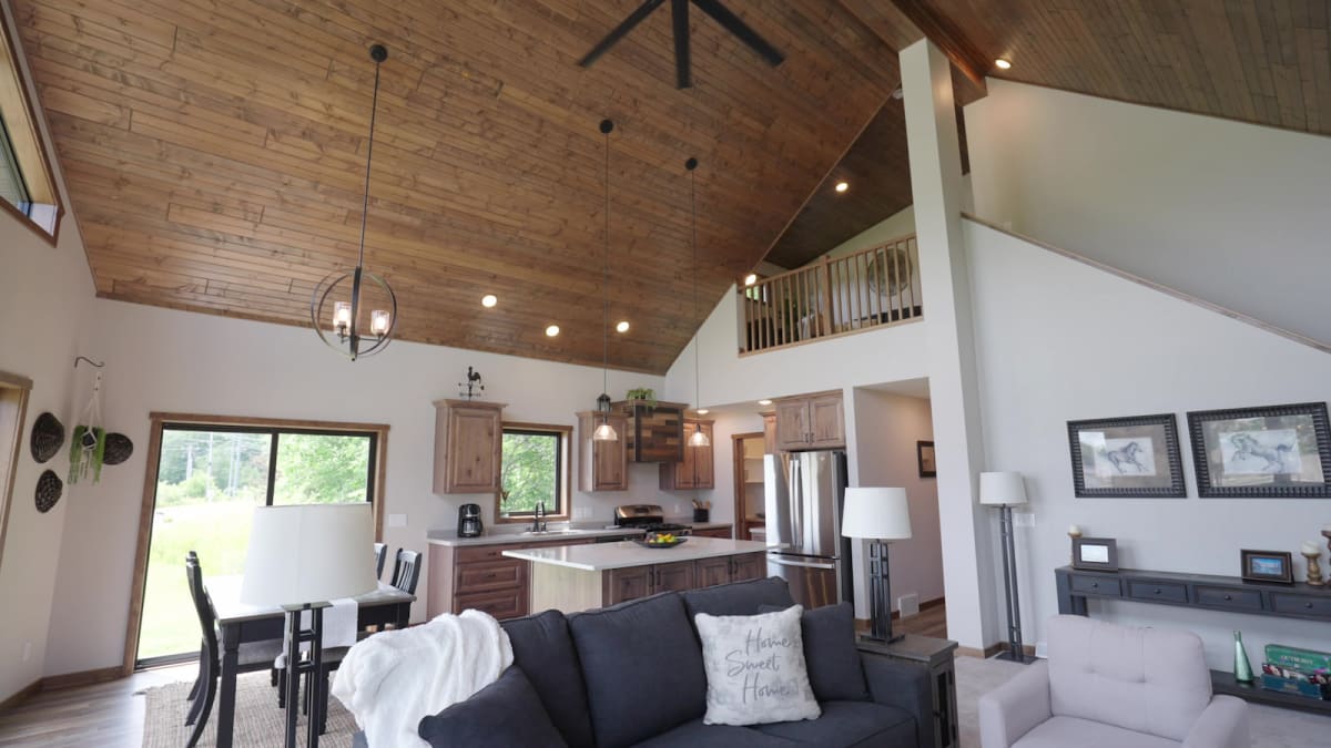Open-concept living area with vaulted wood ceiling, loft, and kitchen by Wisconsin Homes.