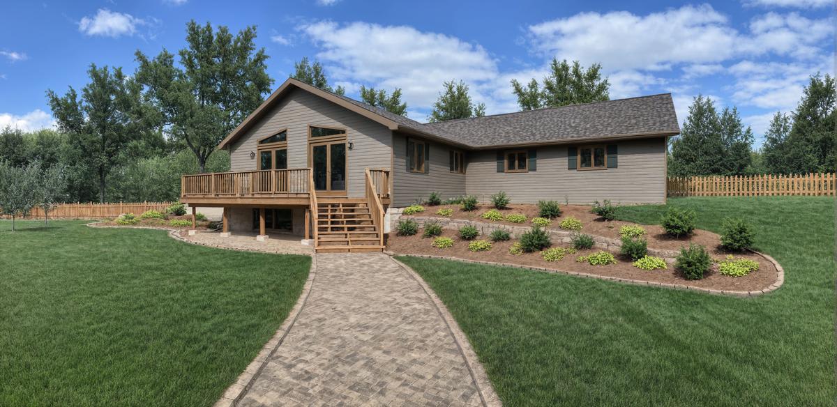 Walkout cottage home by Wisconsin Homes with raised deck, stone walkway, and landscaped garden beds.