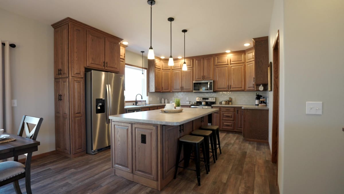 Spacious kitchen with wood cabinetry, center island, and stainless steel appliances by Wisconsin Homes.
