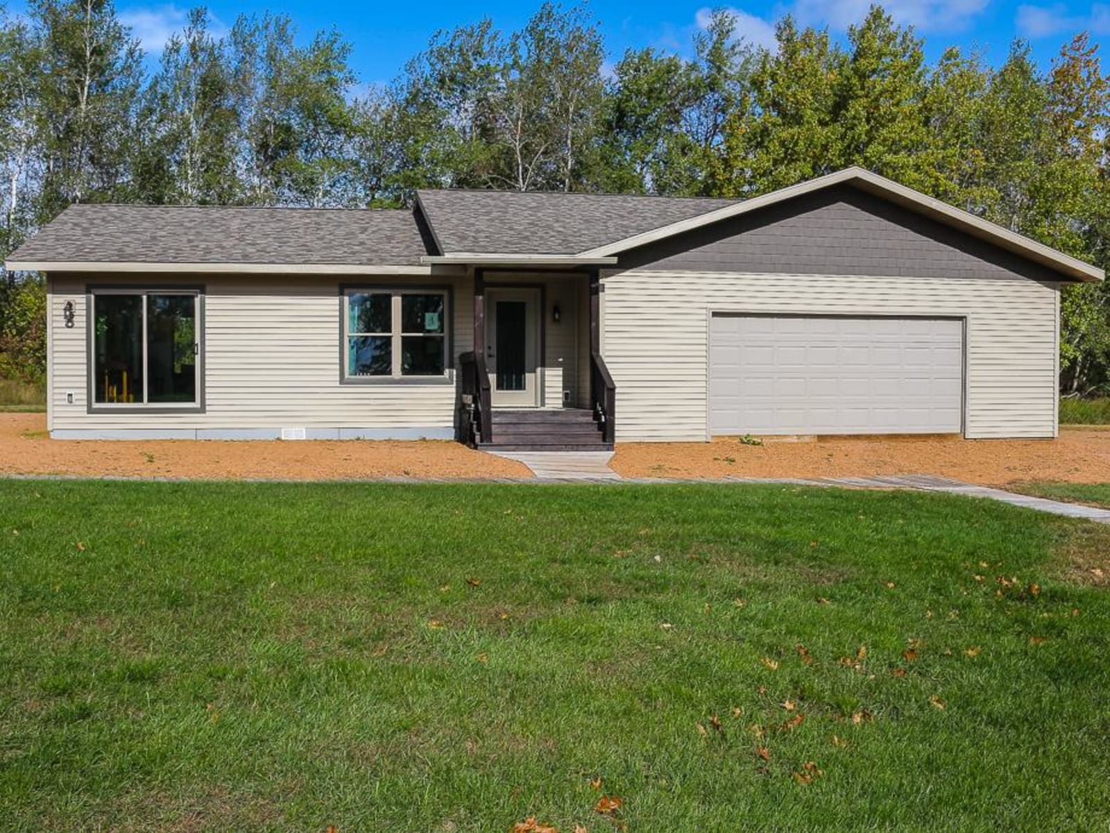 Beige ranch-style modular home with covered entry and attached two-car garage by Wisconsin Homes.