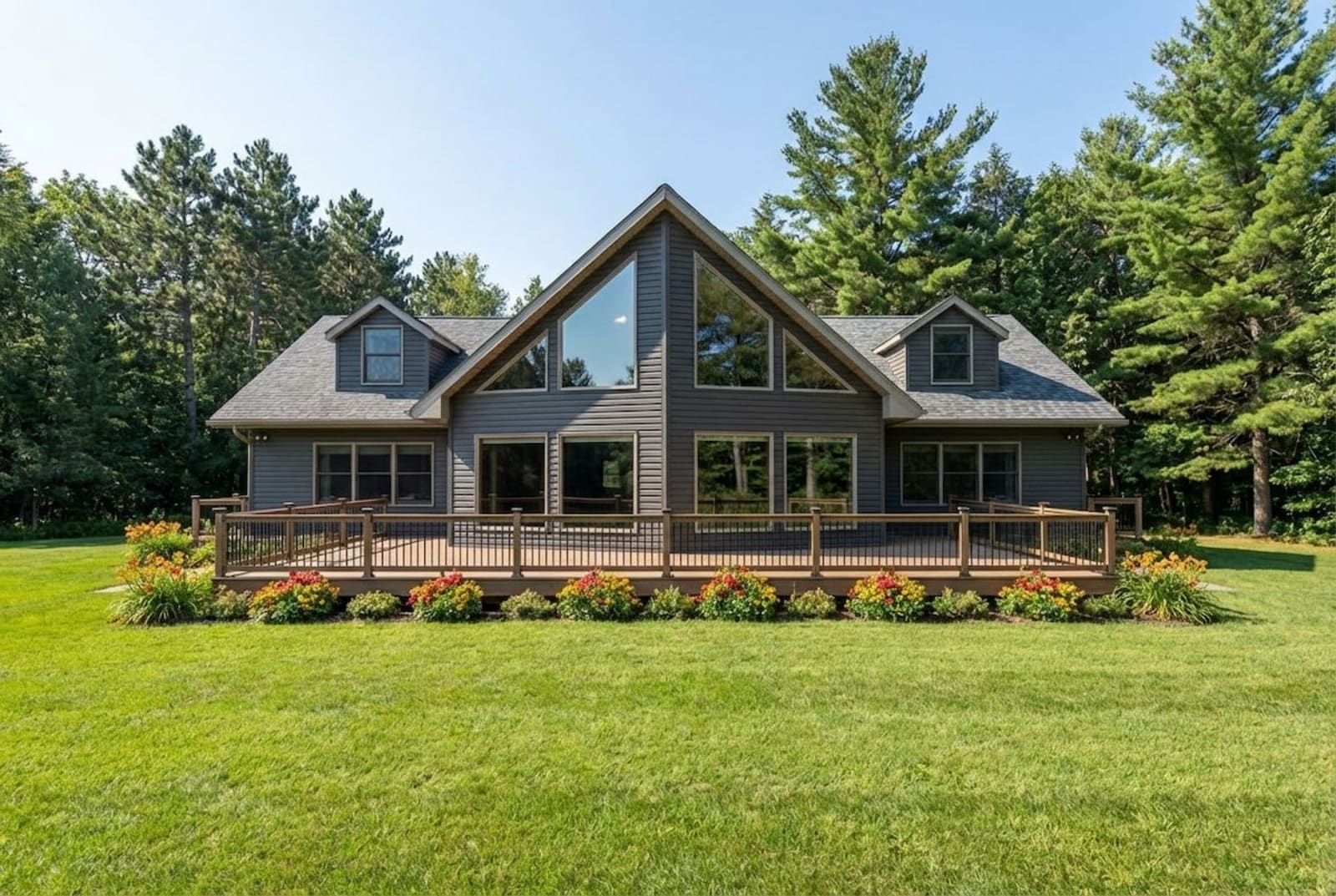 Gray Chalet-style modular home by Wisconsin Homes in Marshfield, WI with full front deck and floor-to-ceiling windows.