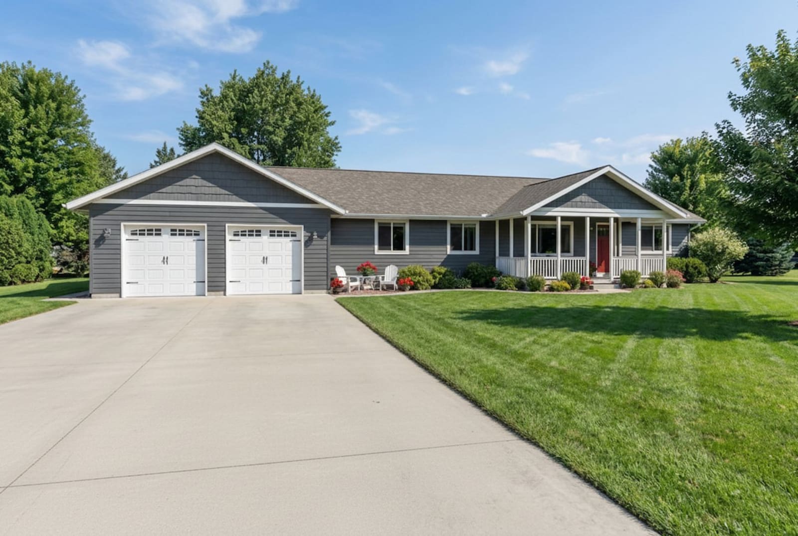 Gray ranch-style modular home by Wisconsin Homes with white garage doors and a covered front porch in Marshfield, WI.