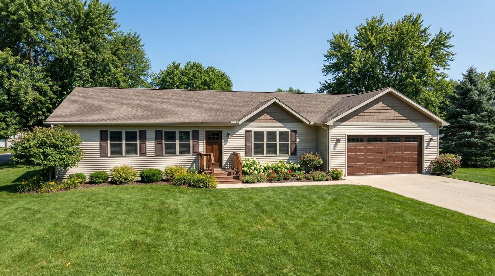 Tan modular home with brown garage door, matching shutters, and landscaped front yard by Wisconsin Homes in Marshfield, WI.