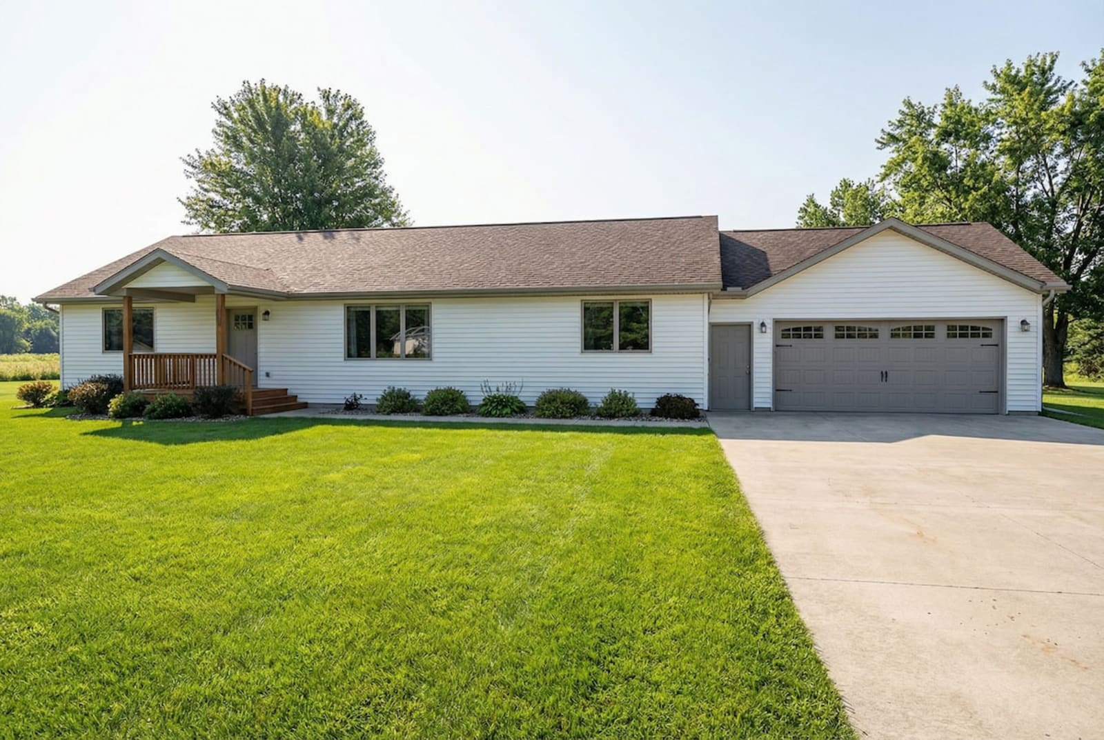 White modular ranch home by Wisconsin Homes with gray garage doors and wood-accented front porch in Marshfield, WI.