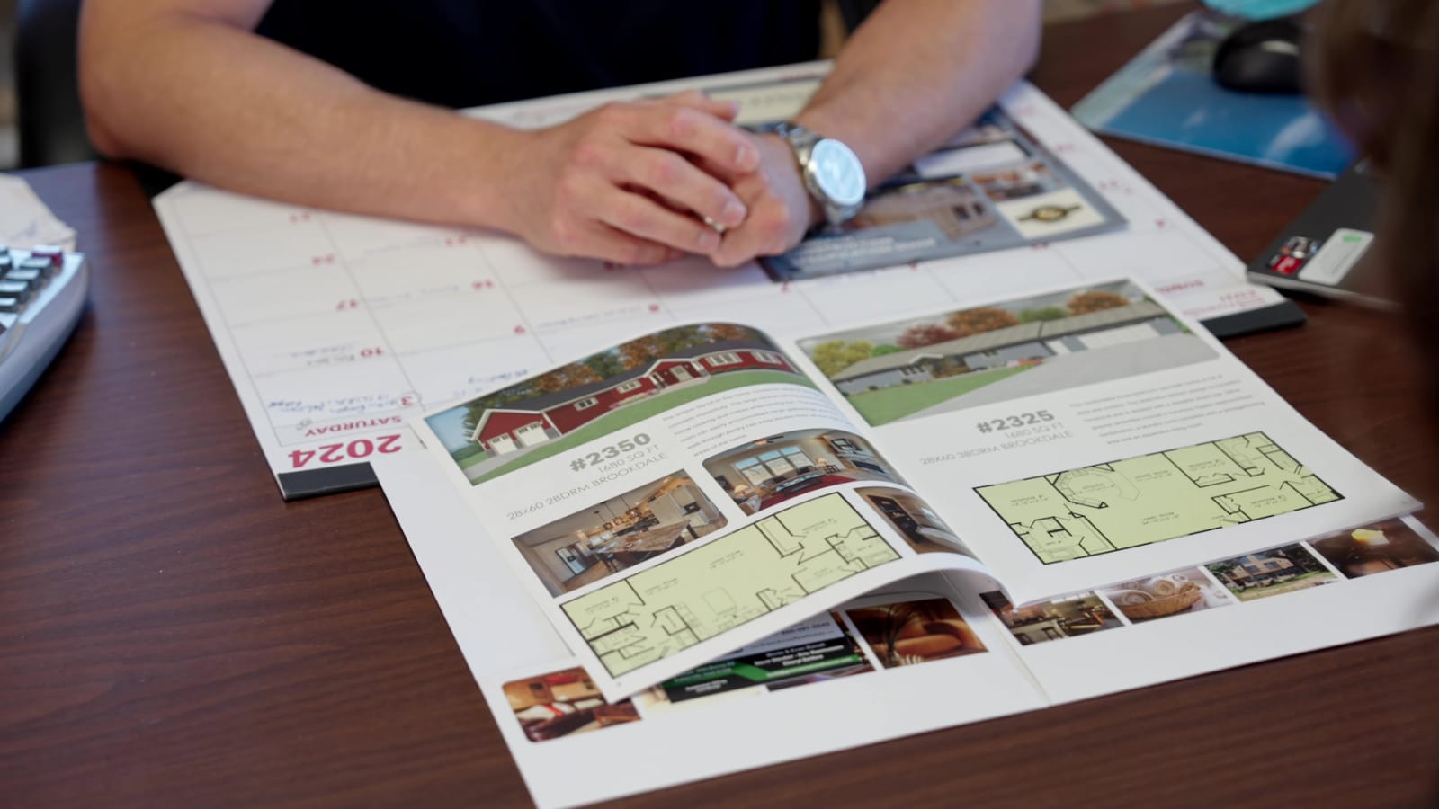 Open brochure showing Wisconsin Homes floor plans and model options during a design consultation.