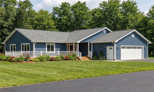 Blue cottage-style modular home by Wisconsin Homes in Marshfield, WI with white trim, front porch, and attached garage.