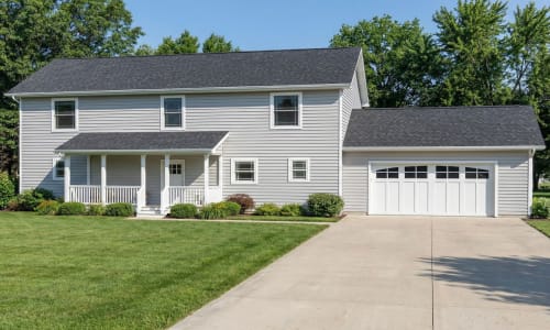 Light gray Colonial-style modular home by Wisconsin Homes in Marshfield, WI with covered porch and attached garage.