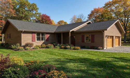 Rustic cottage-style modular home by Wisconsin Homes in Marshfield, WI with wood siding, red shutters, and attached garage.