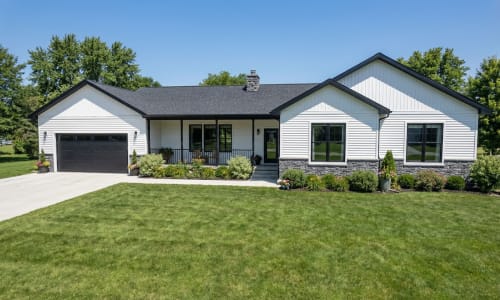 White ranch-style modular home by Wisconsin Homes with black trim, stone base, and black garage door in Marshfield, WI.