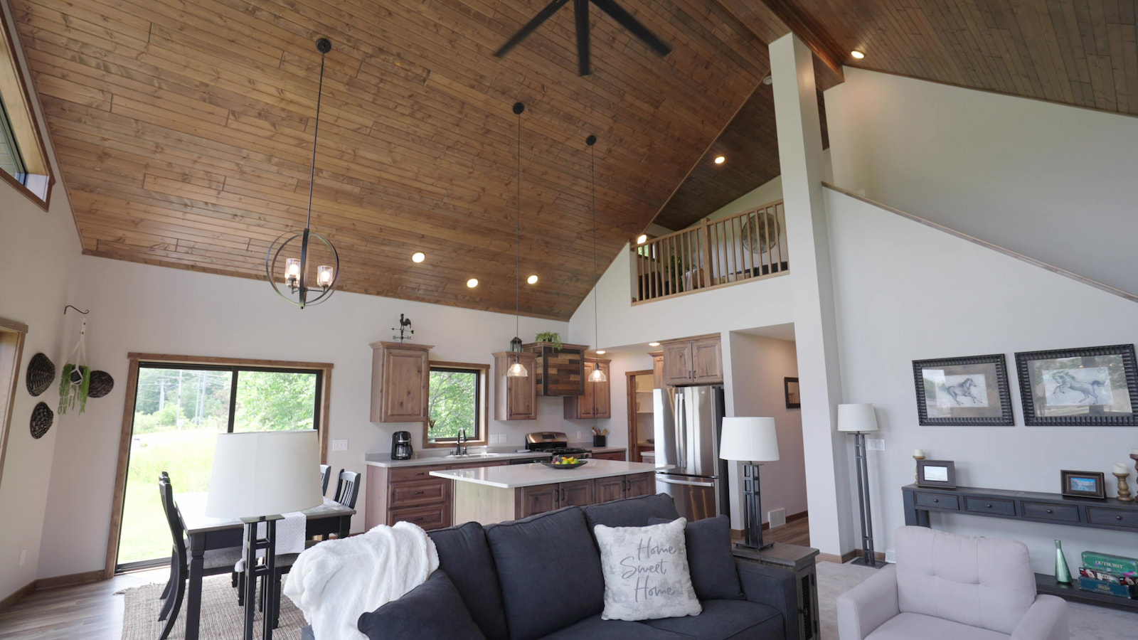 Open-concept living area with vaulted wood ceiling, loft, and kitchen by Wisconsin Homes.