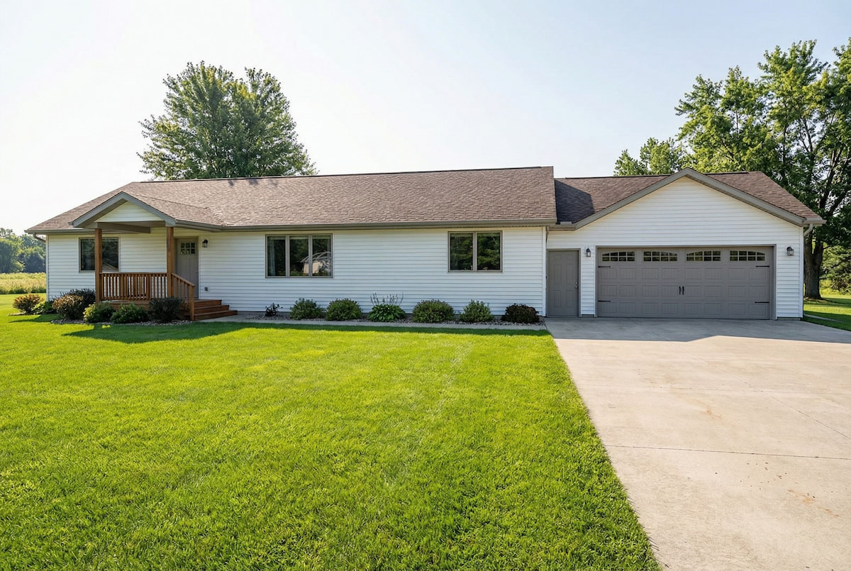 White modular ranch home by Wisconsin Homes with gray garage doors and wood-accented front porch in Marshfield, WI.