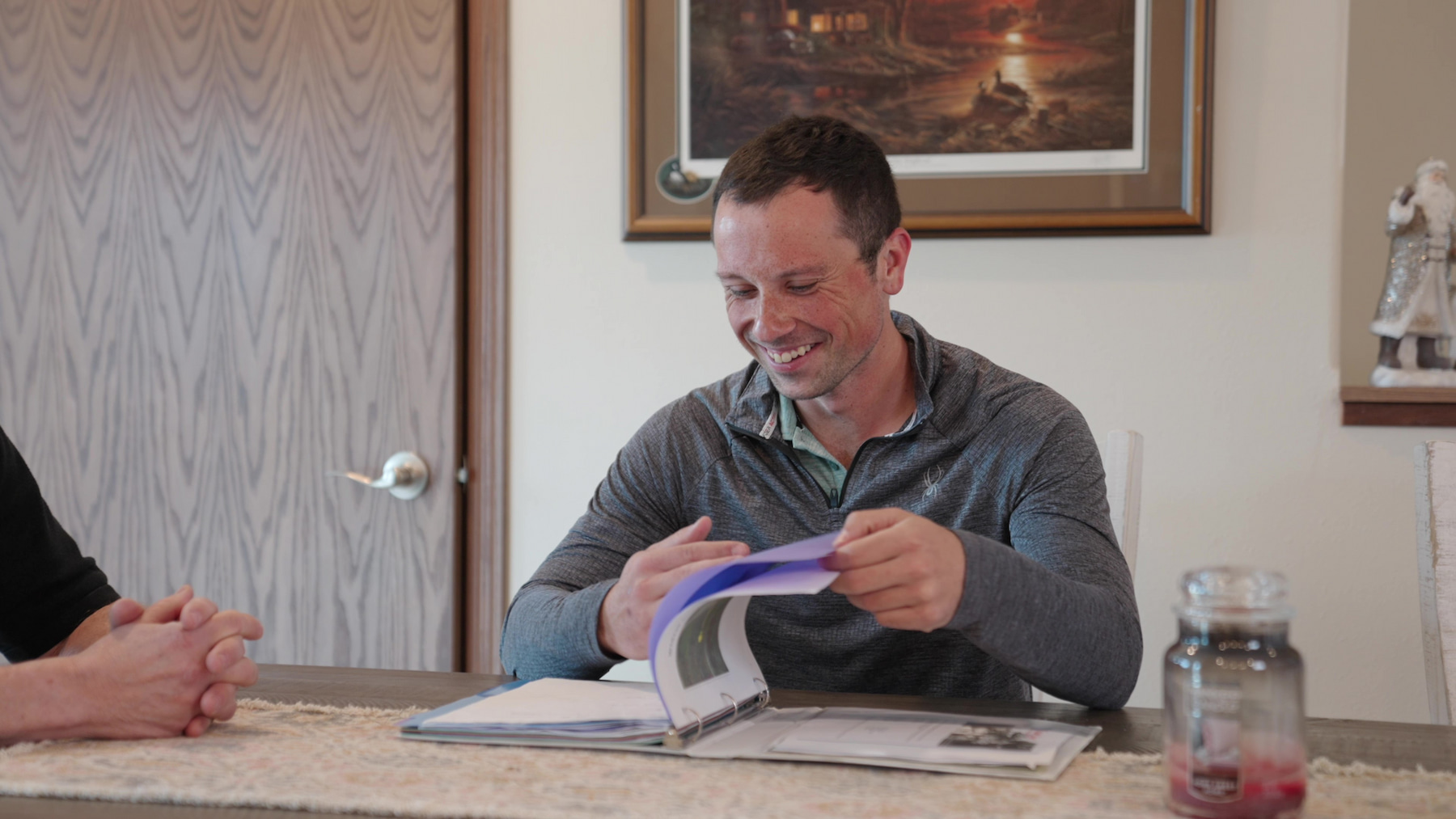 Homeowner smiling while reviewing modular home plans at a dining table during the Wisconsin Homes process.