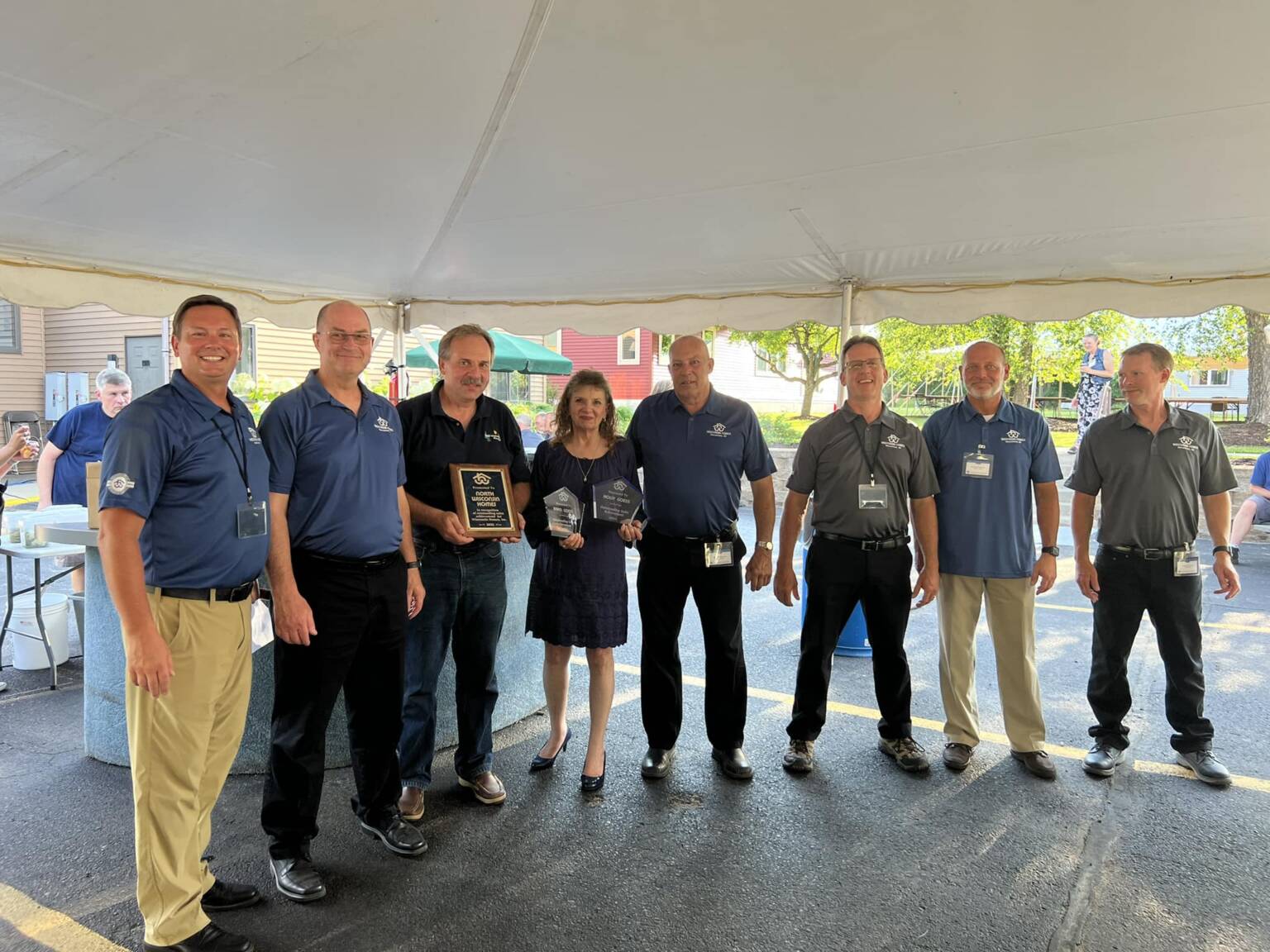 Wisconsin Homes leadership team poses with award plaques at a home builder recognition event under a tent.